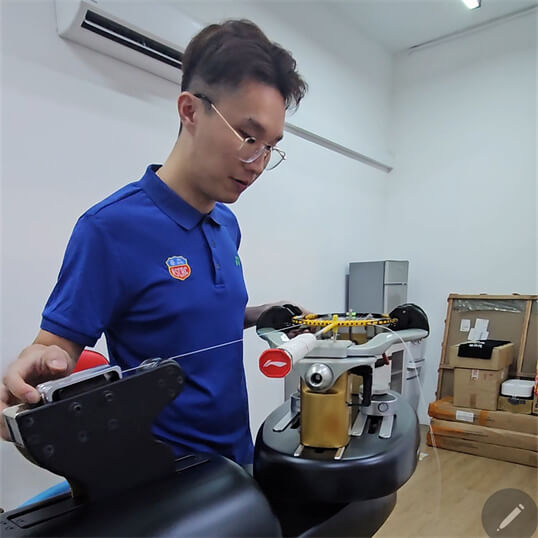 BSW trainer demonstrating proper tension control to Ricky Chen during badminton stringing course