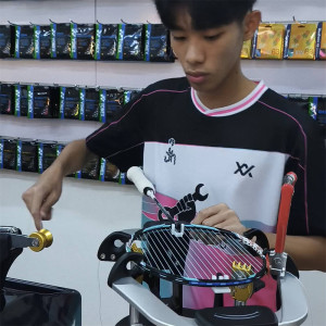Yoon Jun Hin (Reece) practising badminton racquet stringing at a stringing machine