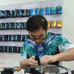Ng Kim Way manipule la corde avec les deux mains au-dessus d’une raquette de badminton montée sur la machine