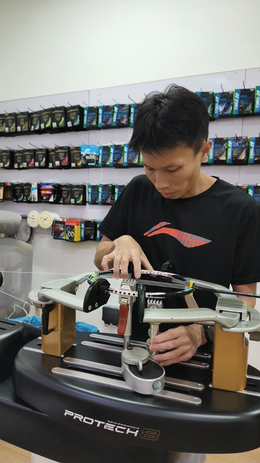 Koh Jian Long Kelvin positioning a string clamp on a mounted badminton racquet Koh Jian Long Kelvin positioning a string clamp on a mounted badminton racquet