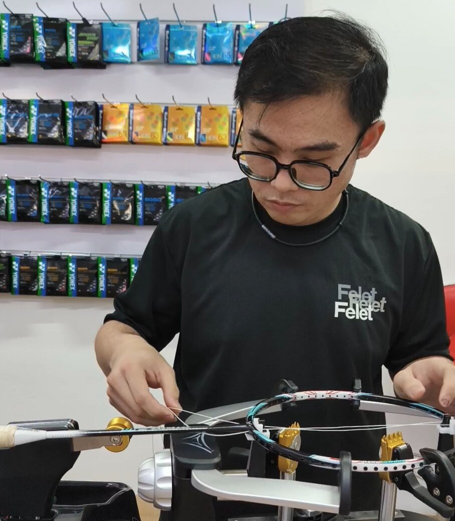 Ng Kim Way guiding loose string across a mounted badminton racquet Ng Kim Way guiding loose string across a mounted badminton racquet