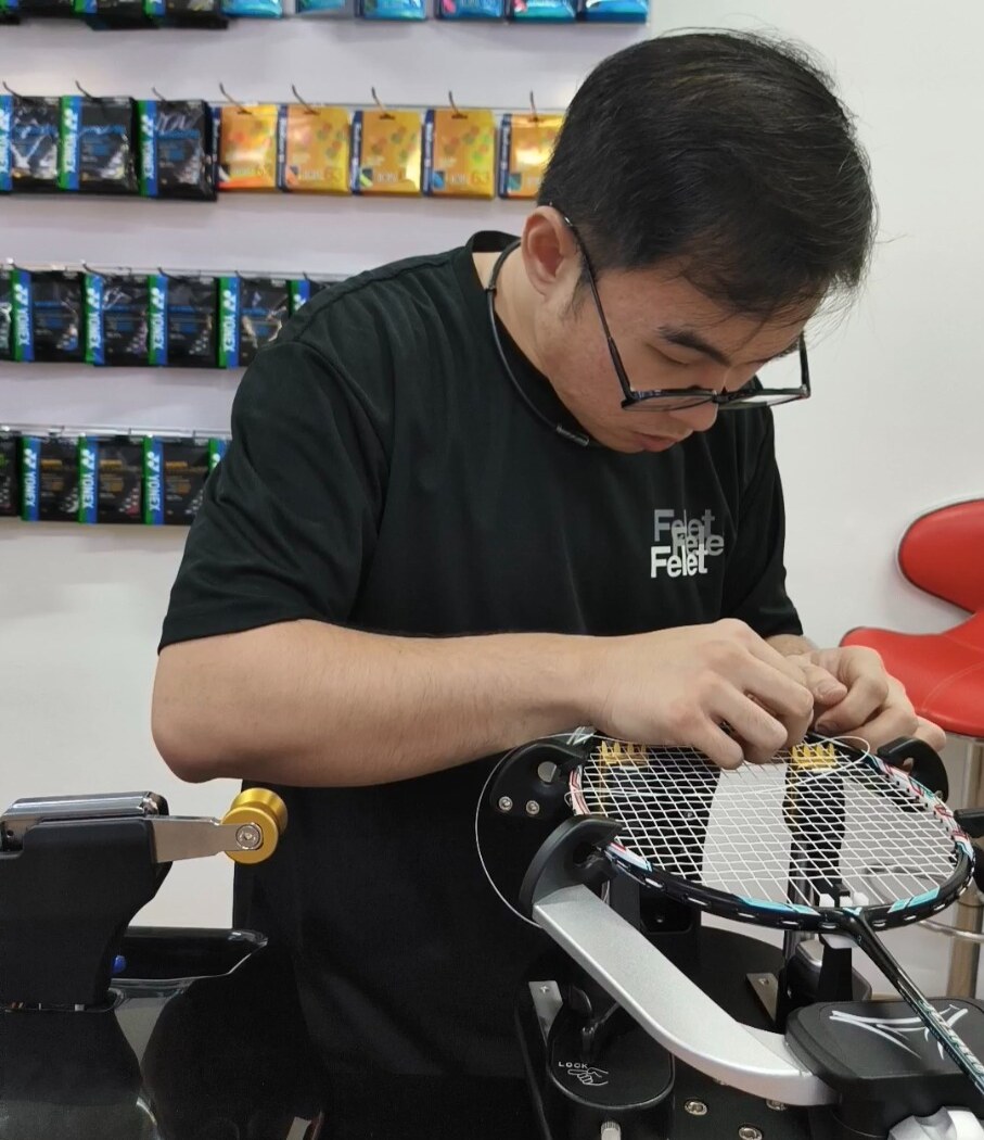 Ng Kim Way handling string near the badminton racquet frame with both hands Ng Kim Way handling string near the badminton racquet frame with both hands