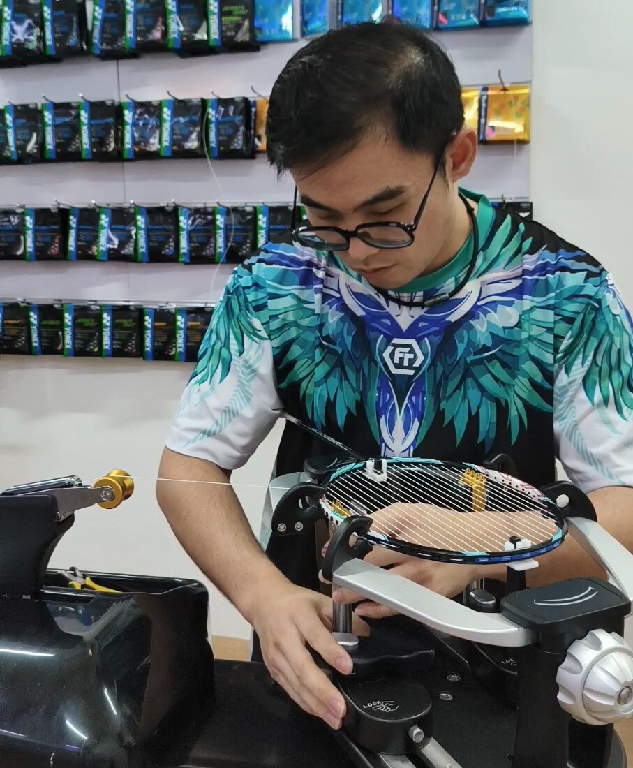 Ng Kim Way adjusting the clamp base beneath a mounted badminton racquet Ng Kim Way adjusting the clamp base beneath a mounted badminton racquet