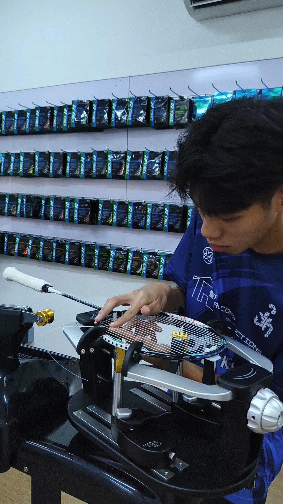 Reece handling a badminton racquet on an electronic stringing machine Reece handling a badminton racquet on an electronic stringing machine